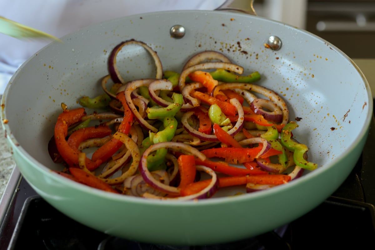 adding onion and peppers to the pan of chili crisp
