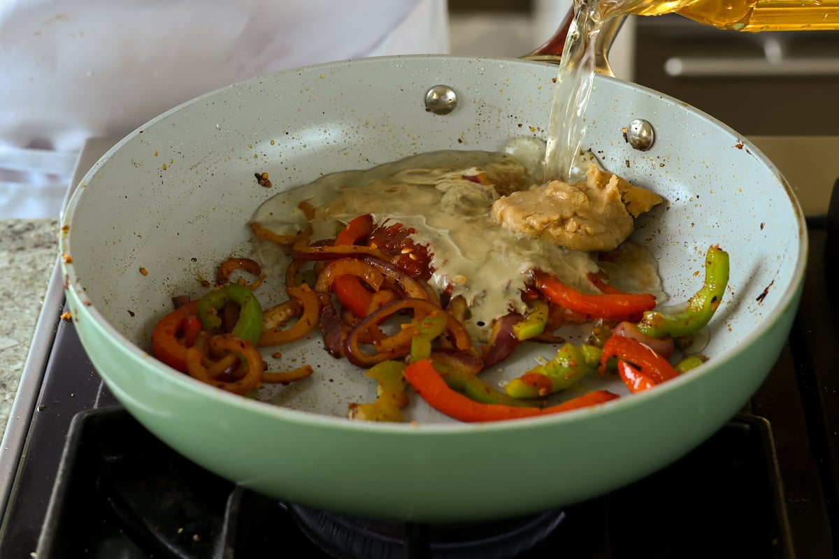 adding more broth ingredients to the pan