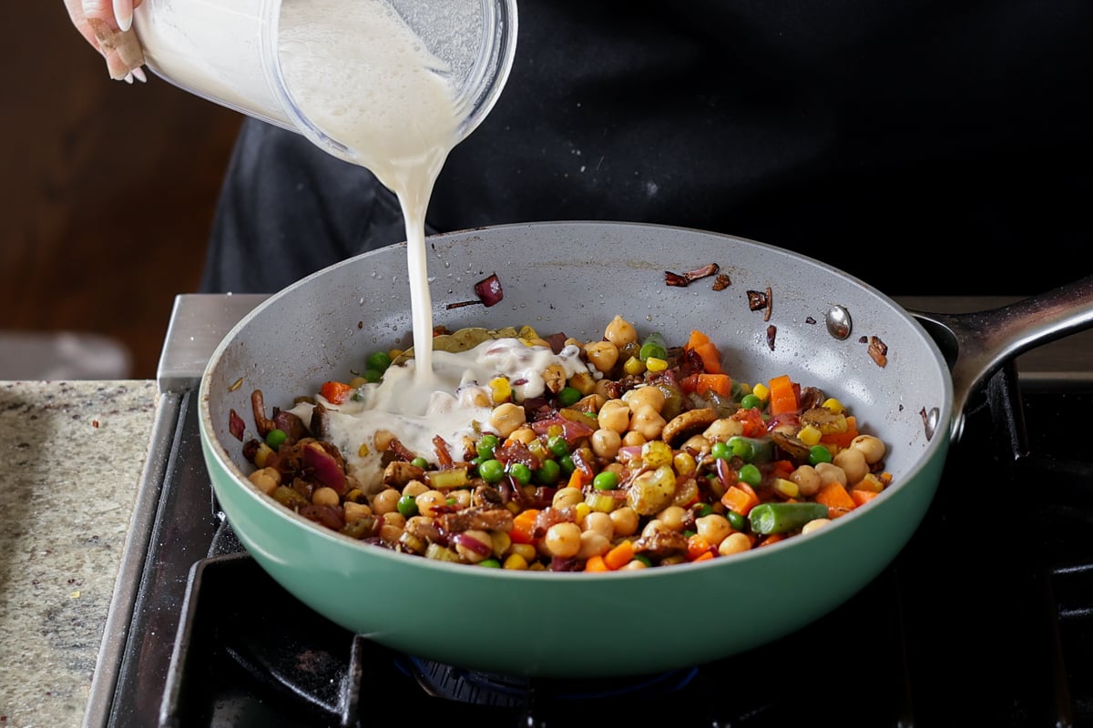 adding cashew cream to pot pie filling in the pan
