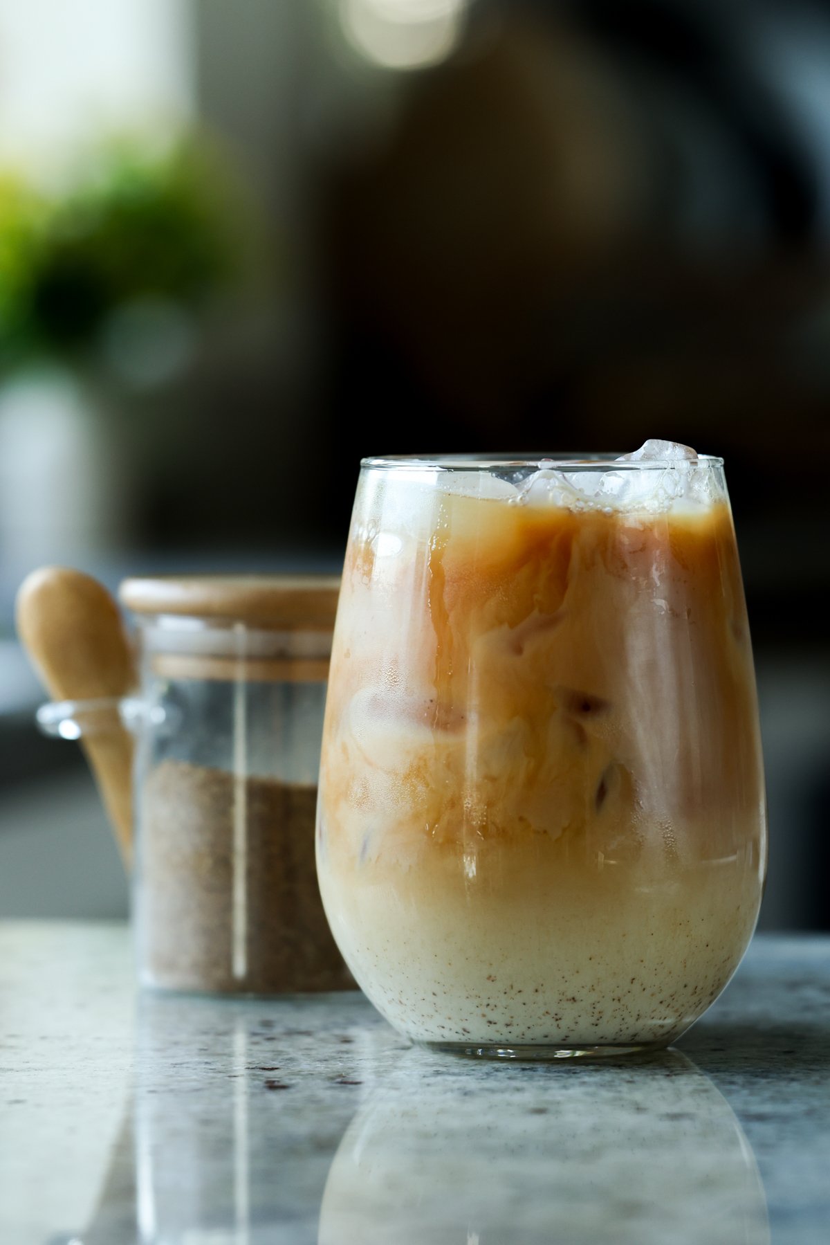glass of iced chai with a jar of chai masala in the background