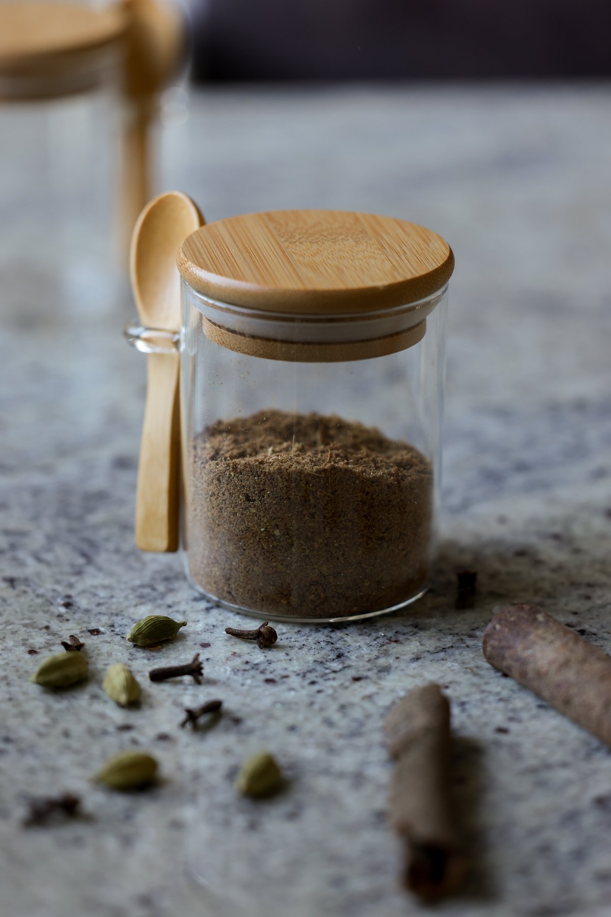 chai spice mix with whole spices on the countertop around it