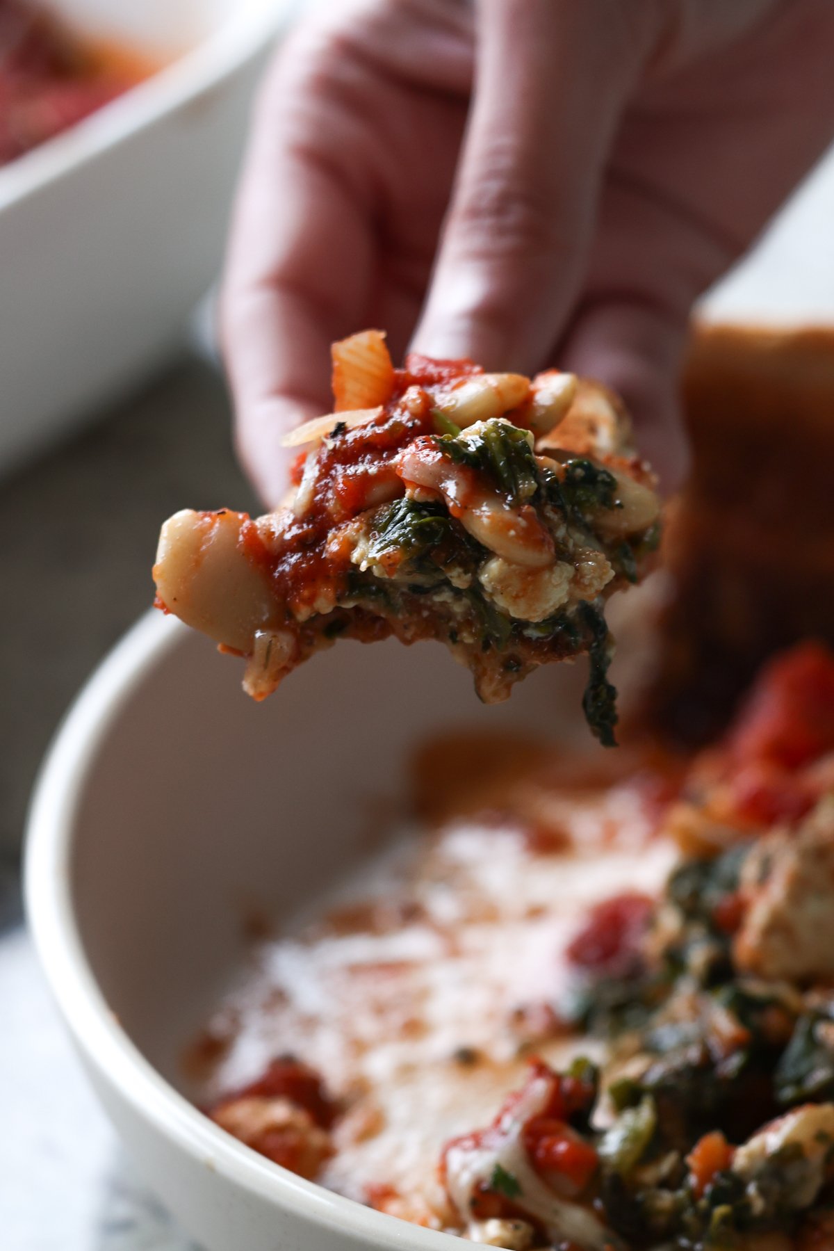 hand scooping up butterbean parmigiana