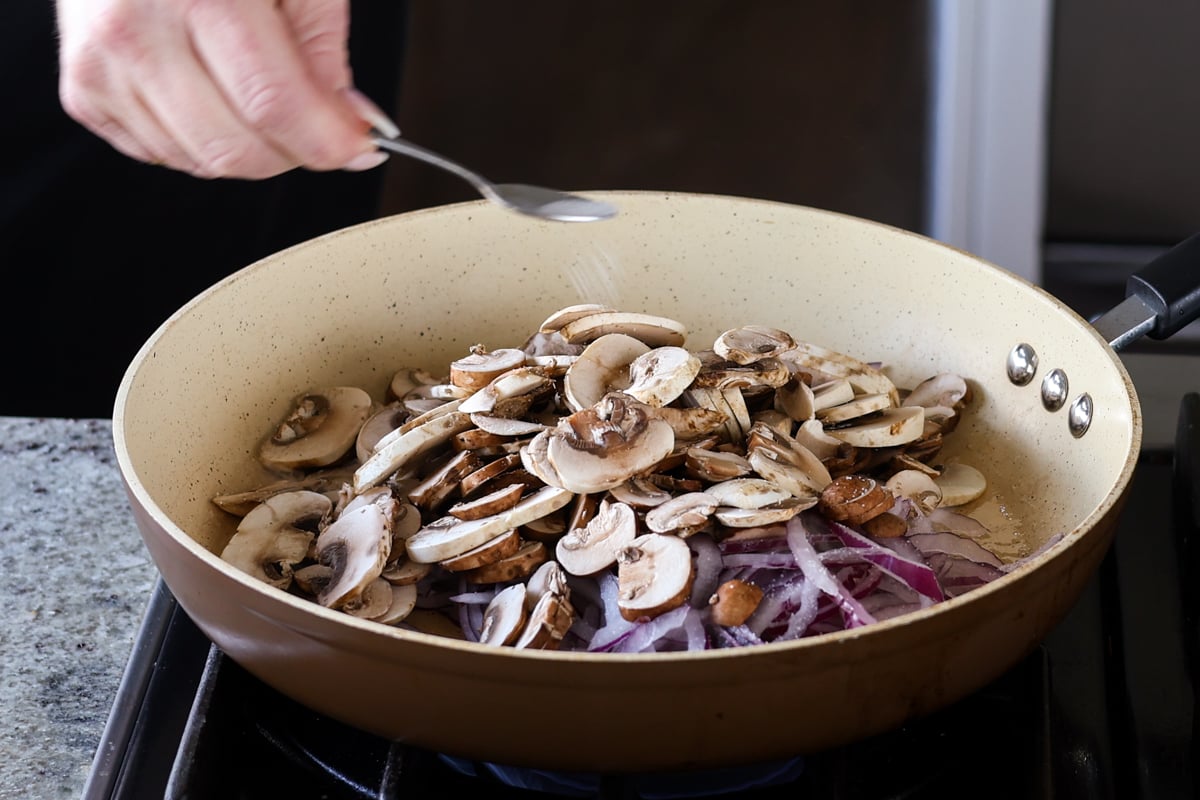 adding salt to the mushrooms and onions