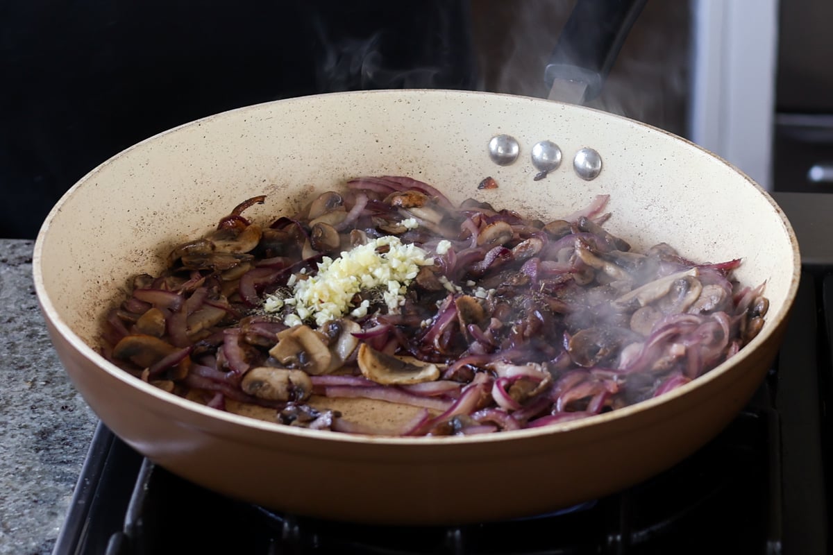 adding garlic to the cooked mushroom mixture