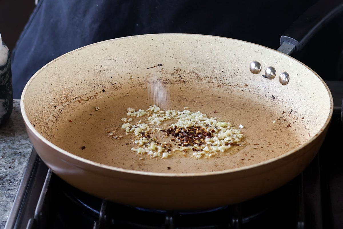 adding garlic and pepper flakes to the pan