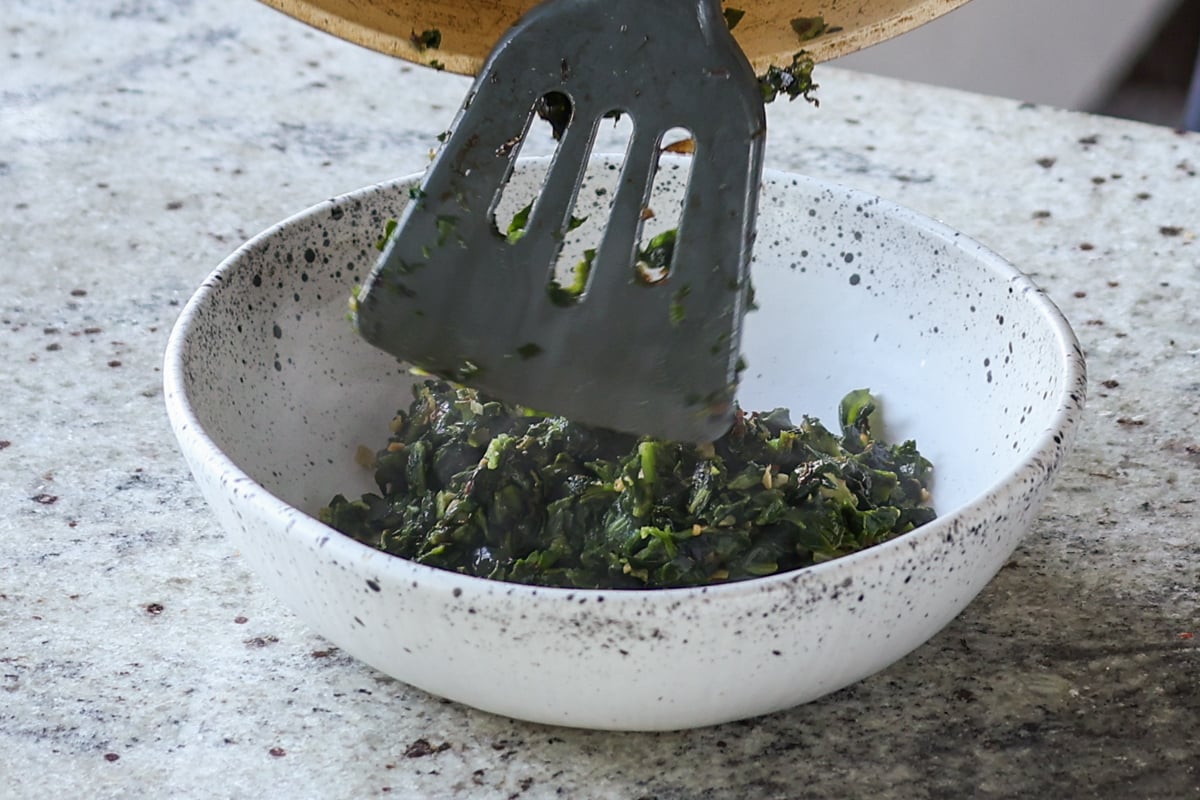 adding spinach mixture to a bowl