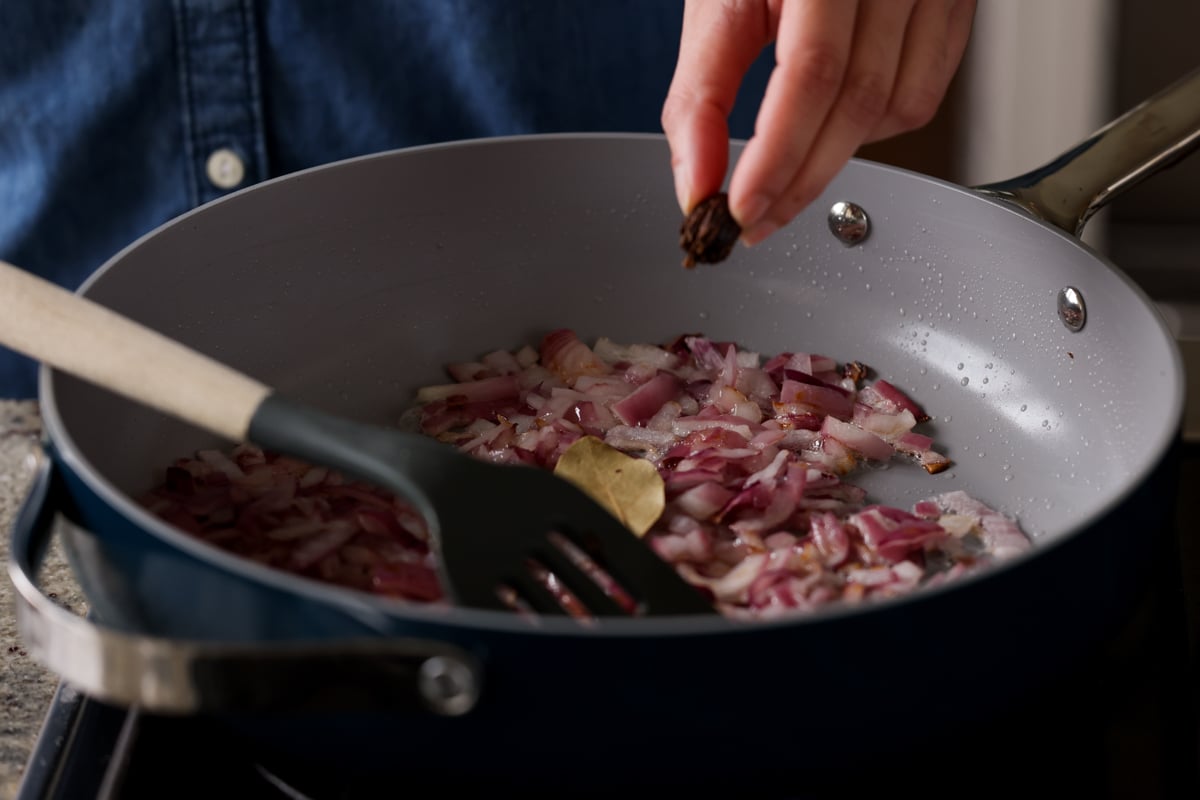 adding whole spices to the onions