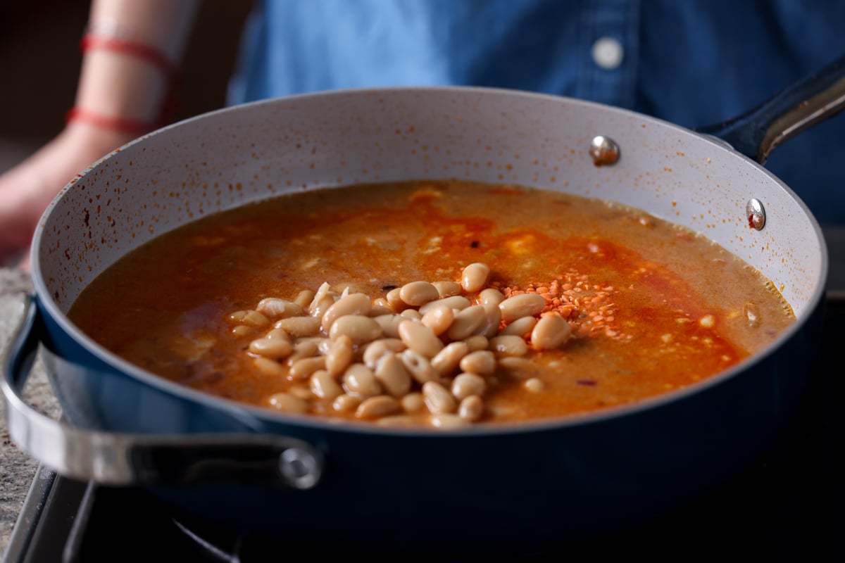 adding white beans to the pan