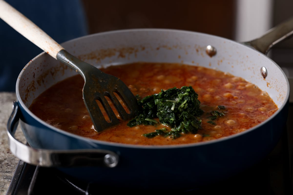 adding spinach to the bean stew