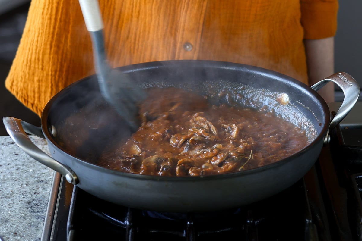 stirring the balchao mushrooms in the pan