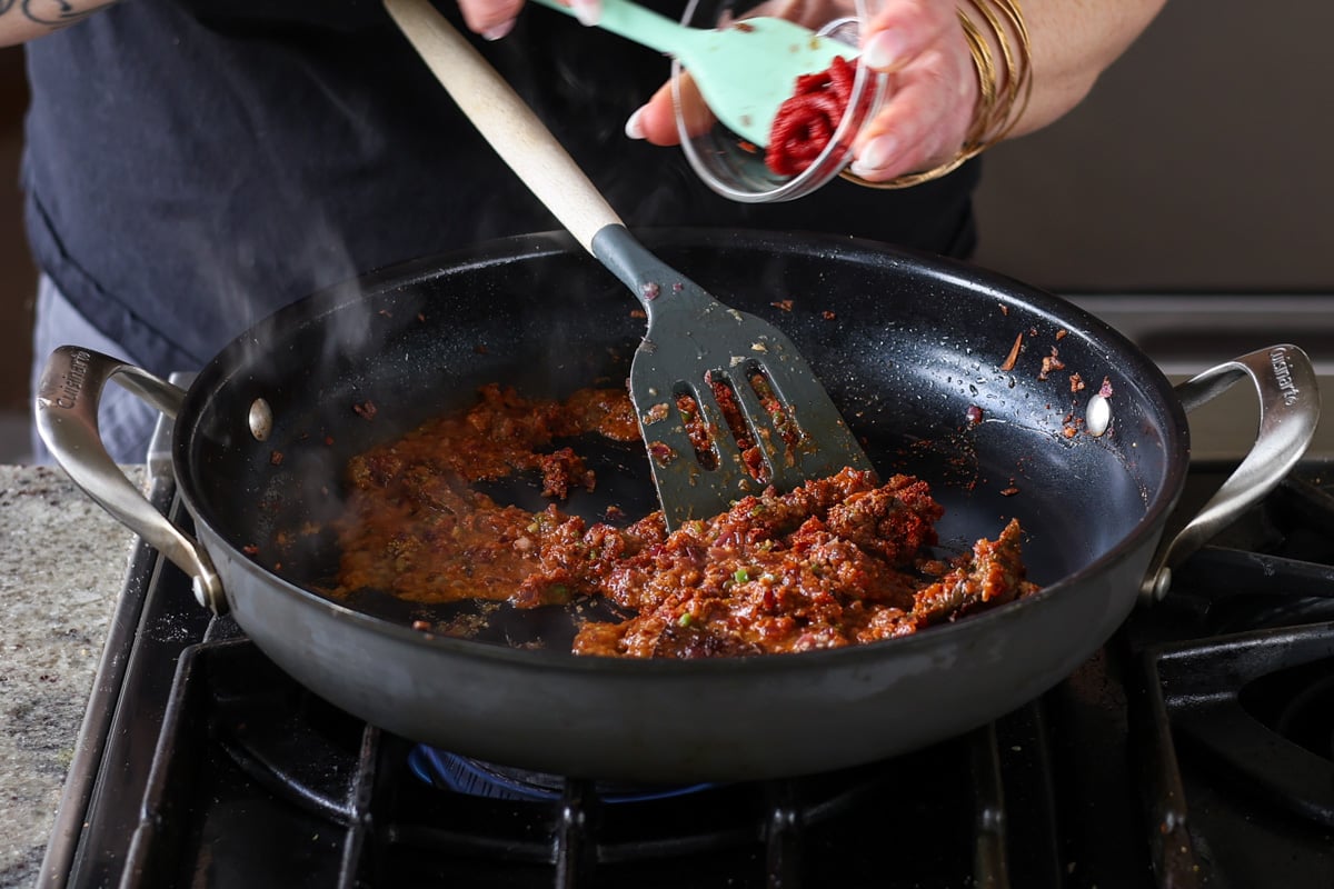 adding tomato paste to the pan