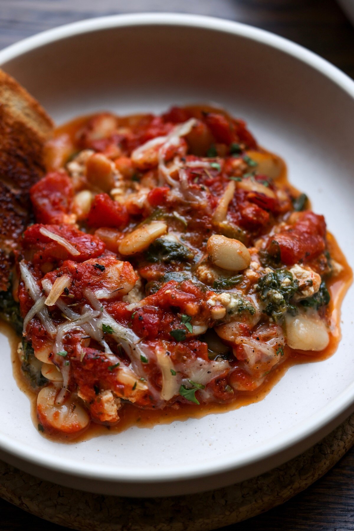 close-up of beans parmigiana in a bowl with garlic bread