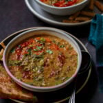 bowls of lentil and spinach soup on a dark table