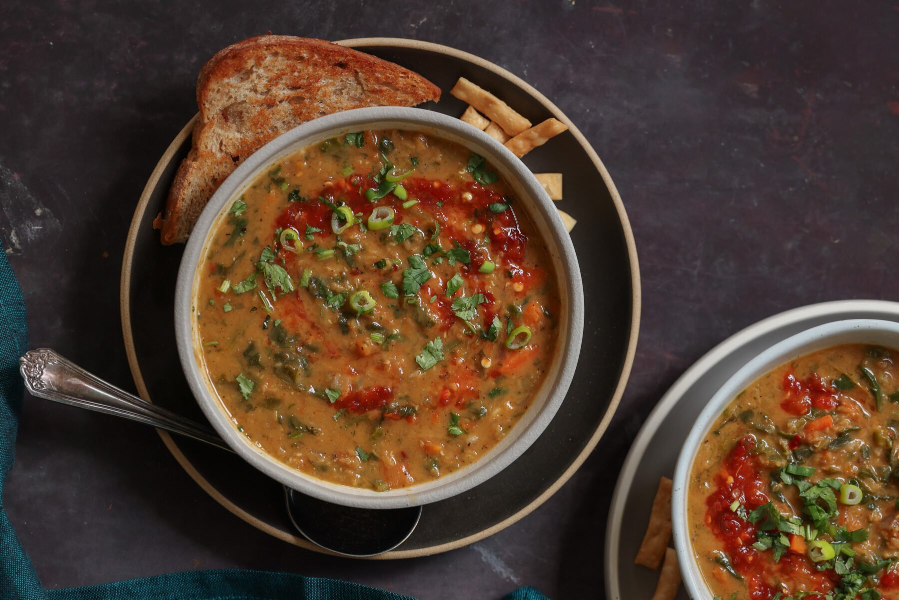 bowls of lentil and spinach soup on a dark table