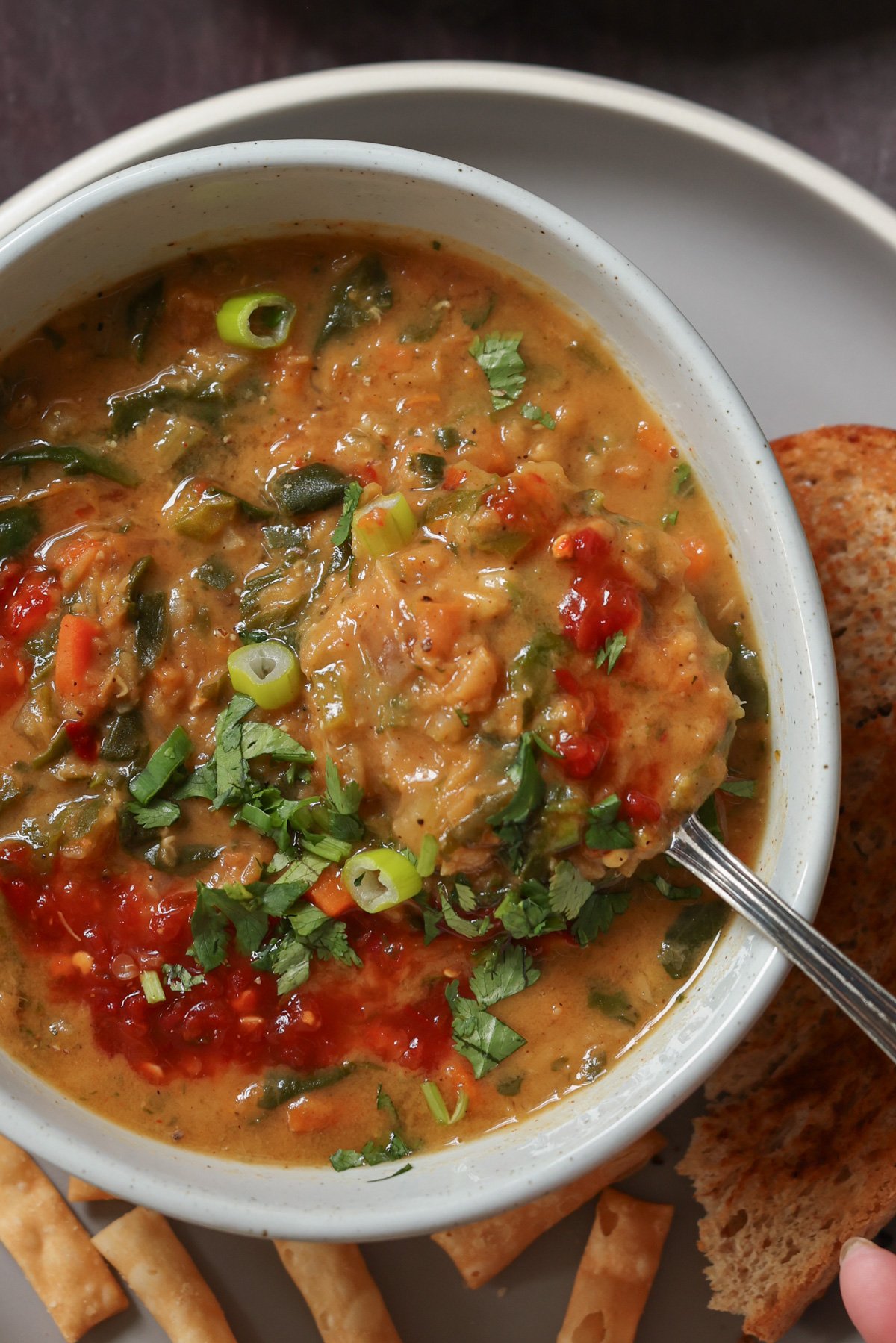 close-up of a spoon scooping a bite of lentil and spinach soup