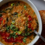 close-up of a spoon scooping a bite of lentil and spinach soup