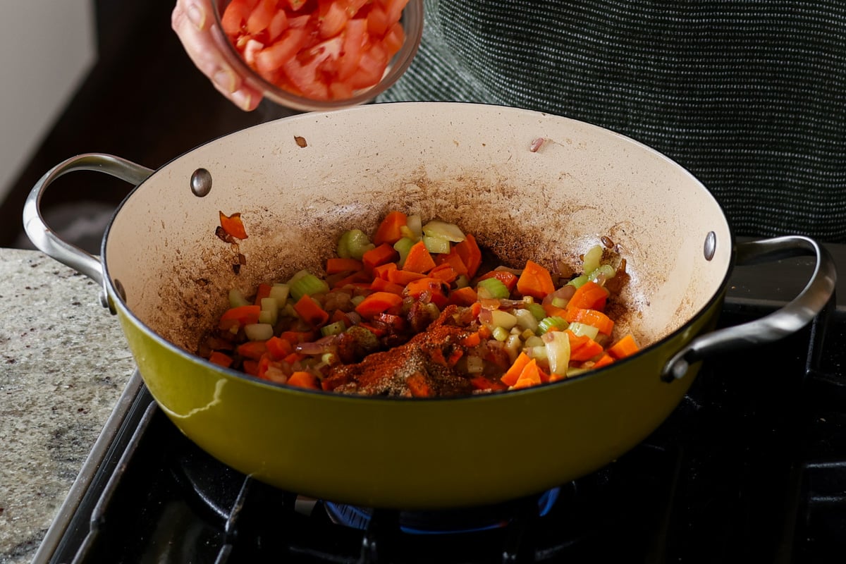 adding tomato to the pan