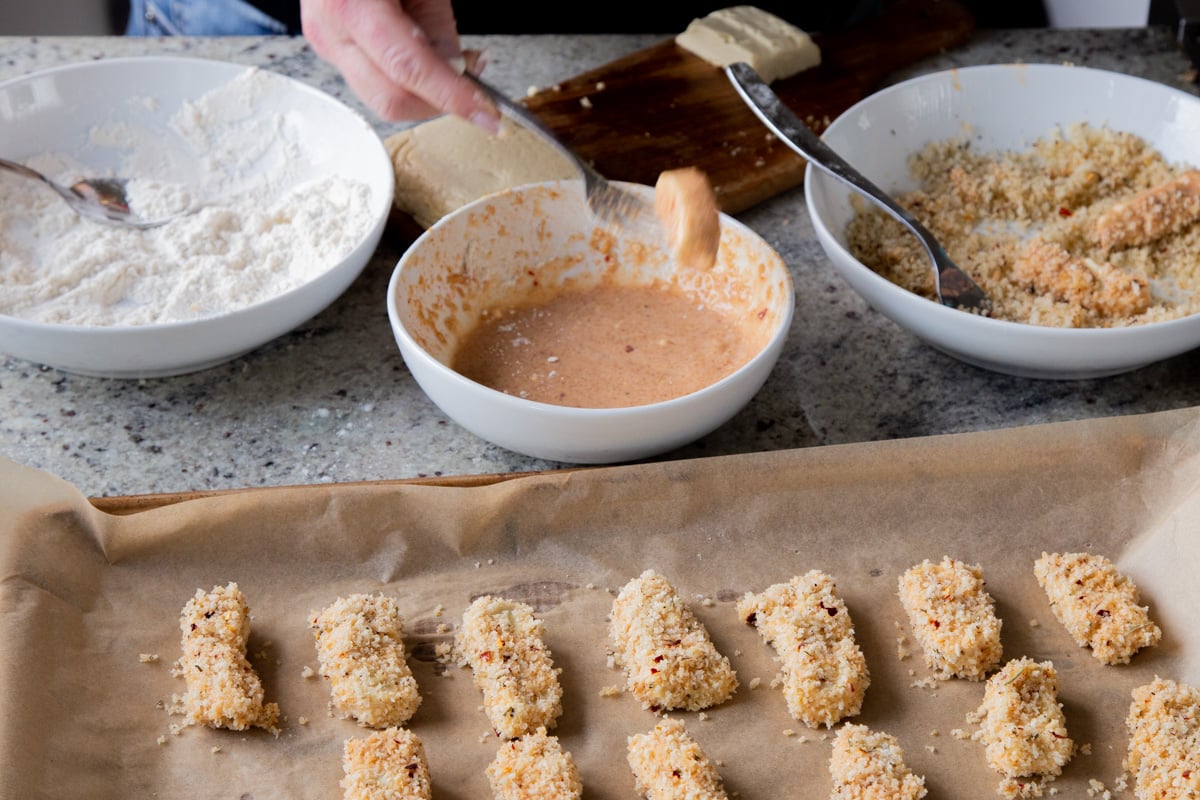 breaded mozzarella sticks on the baking sheet