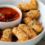 close-up of vegan mozzarella sticks in a serving platter with marinara on the side