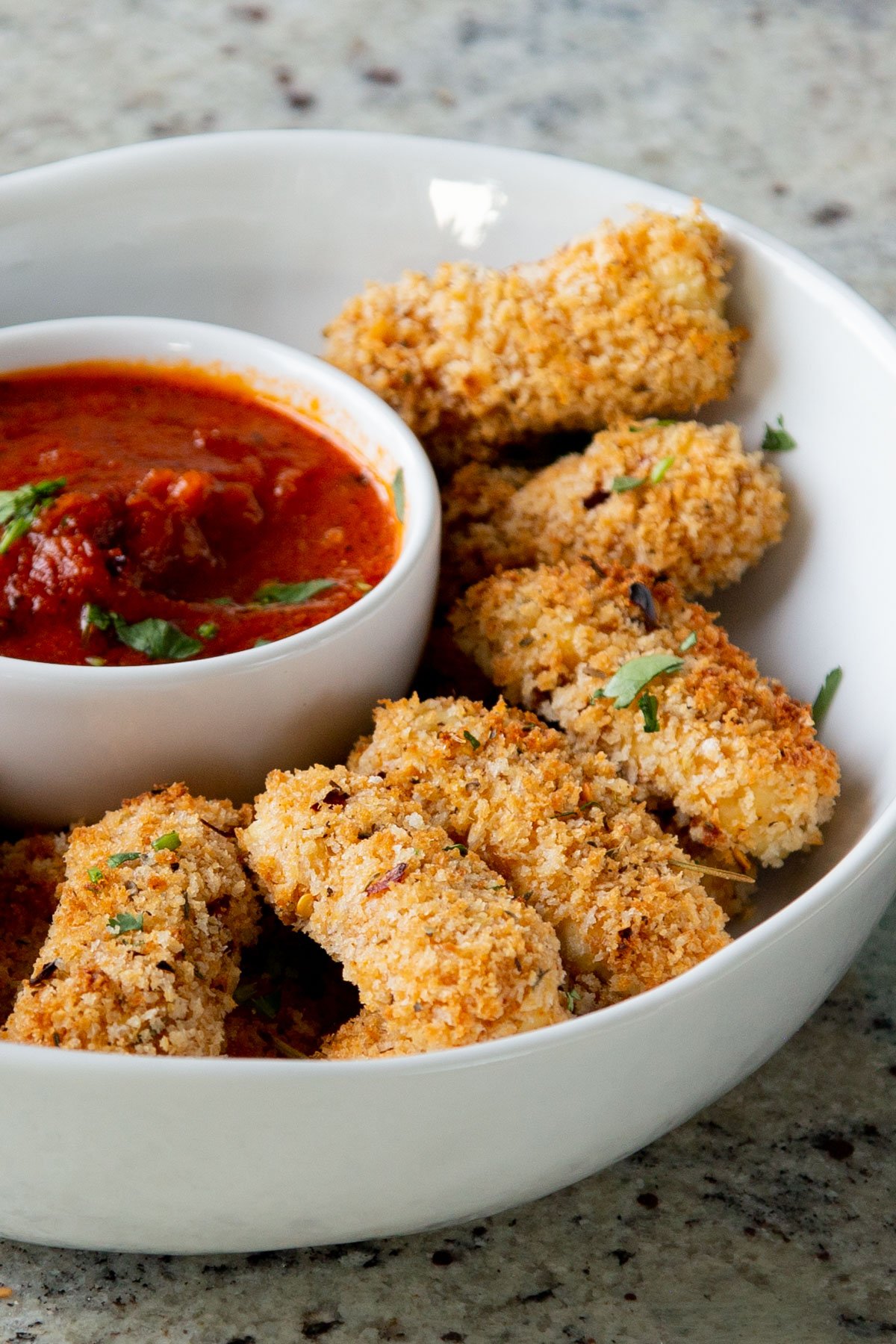close-up of vegan mozzarella sticks in a serving platter with marinara on the side