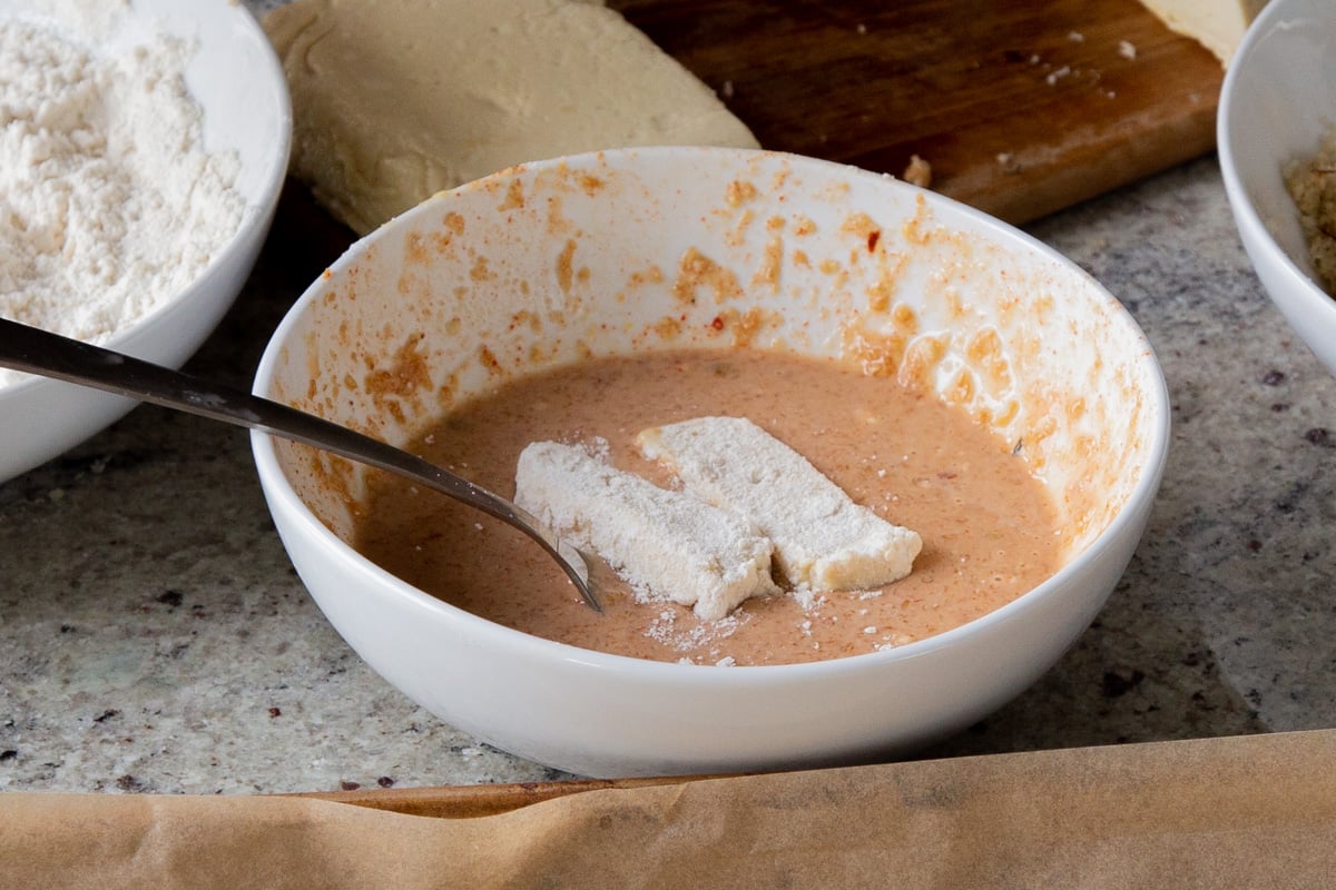 dredging the vegan mozzarella sticks in the milk mixture