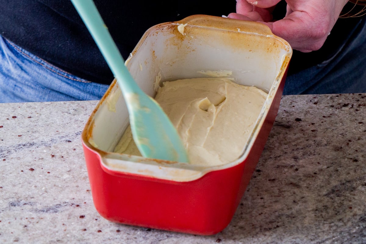 spreading thickened vegan mozzarella into a lined loaf pan