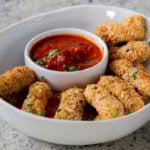 vegan mozzarella sticks in a serving platter with marinara on the side