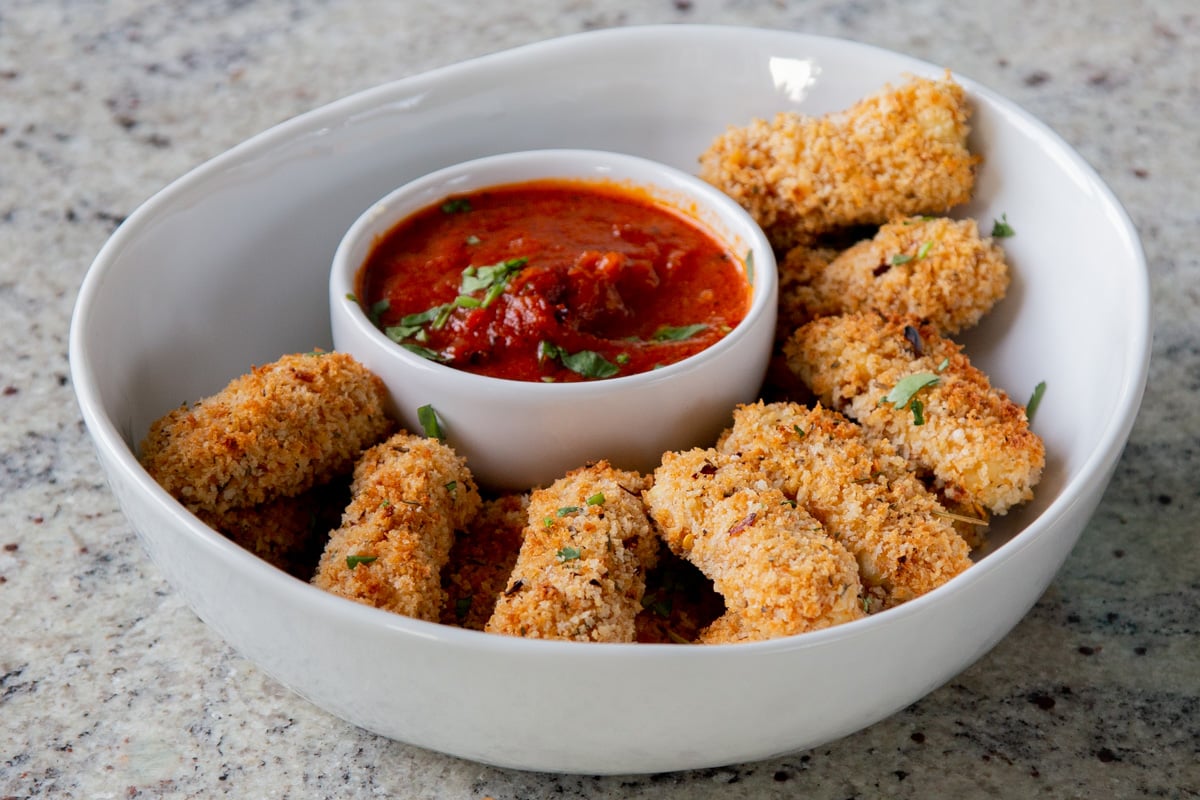 vegan mozzarella sticks in a serving platter with marinara on the side