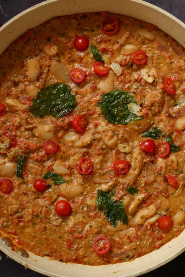 sicilian pesto sauce butter beans in the pan topped with crispy basil