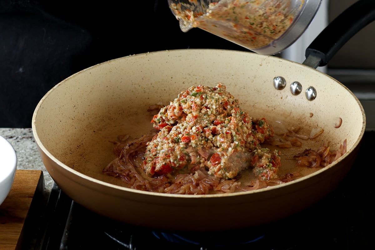 adding Sicilian pesto sauce to the pan of cooked onion