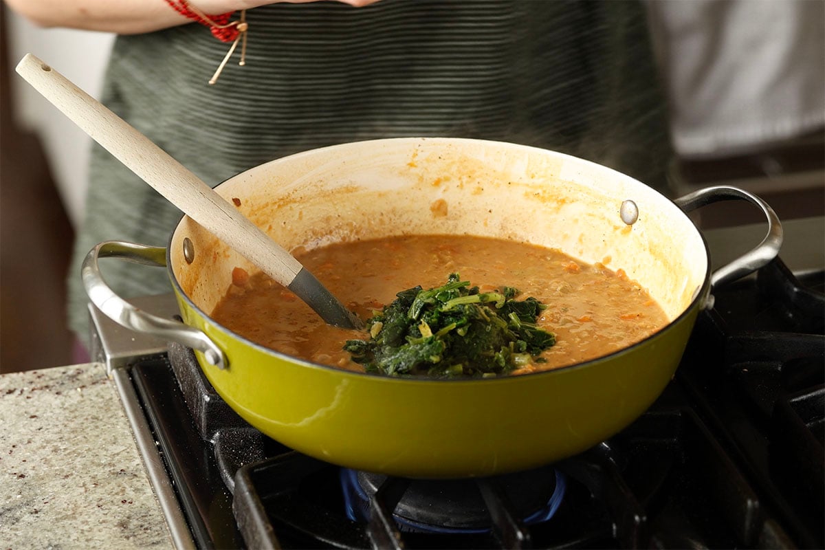 adding spinach to the lentil soup