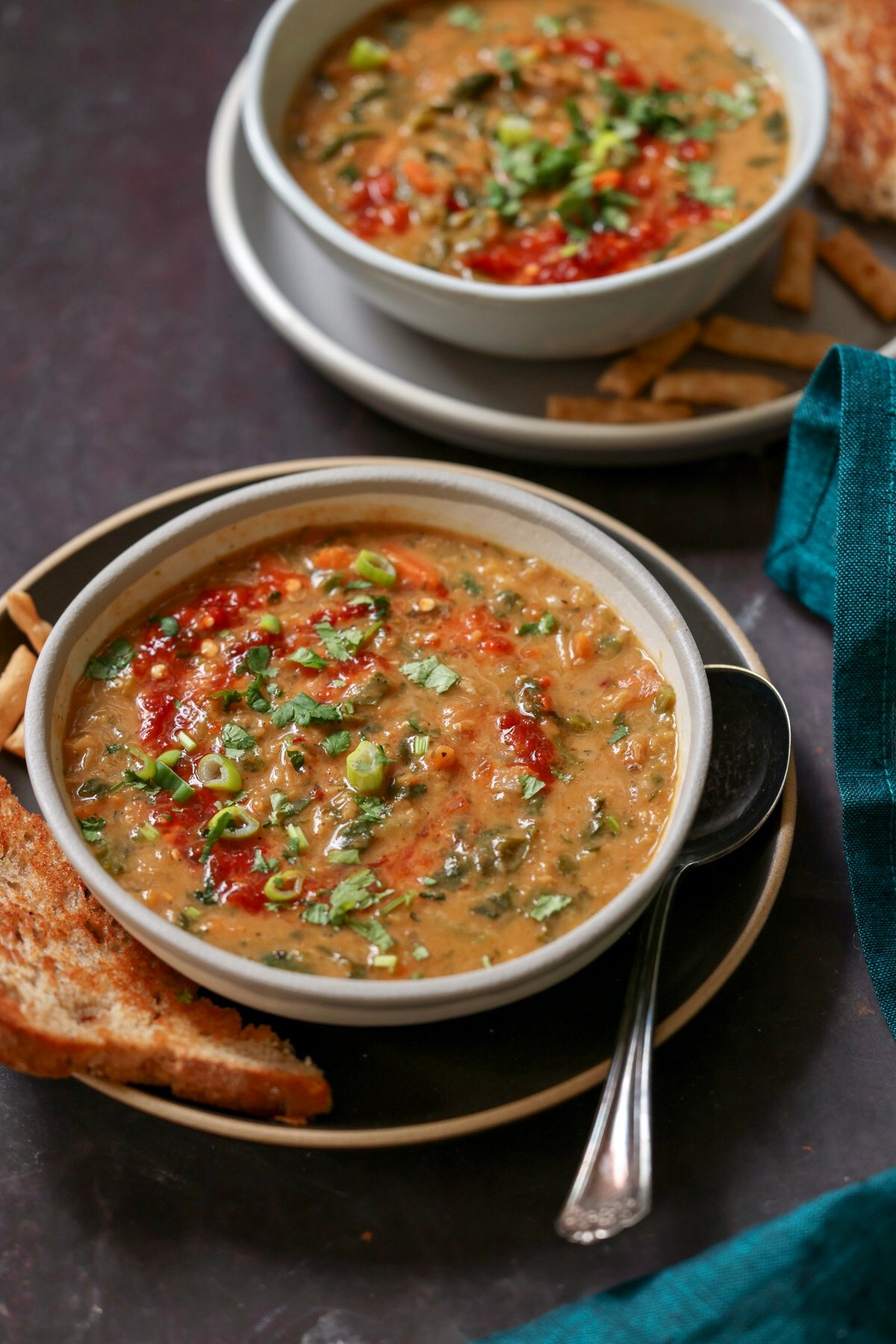bowls of lentil spinach soup on a dark table