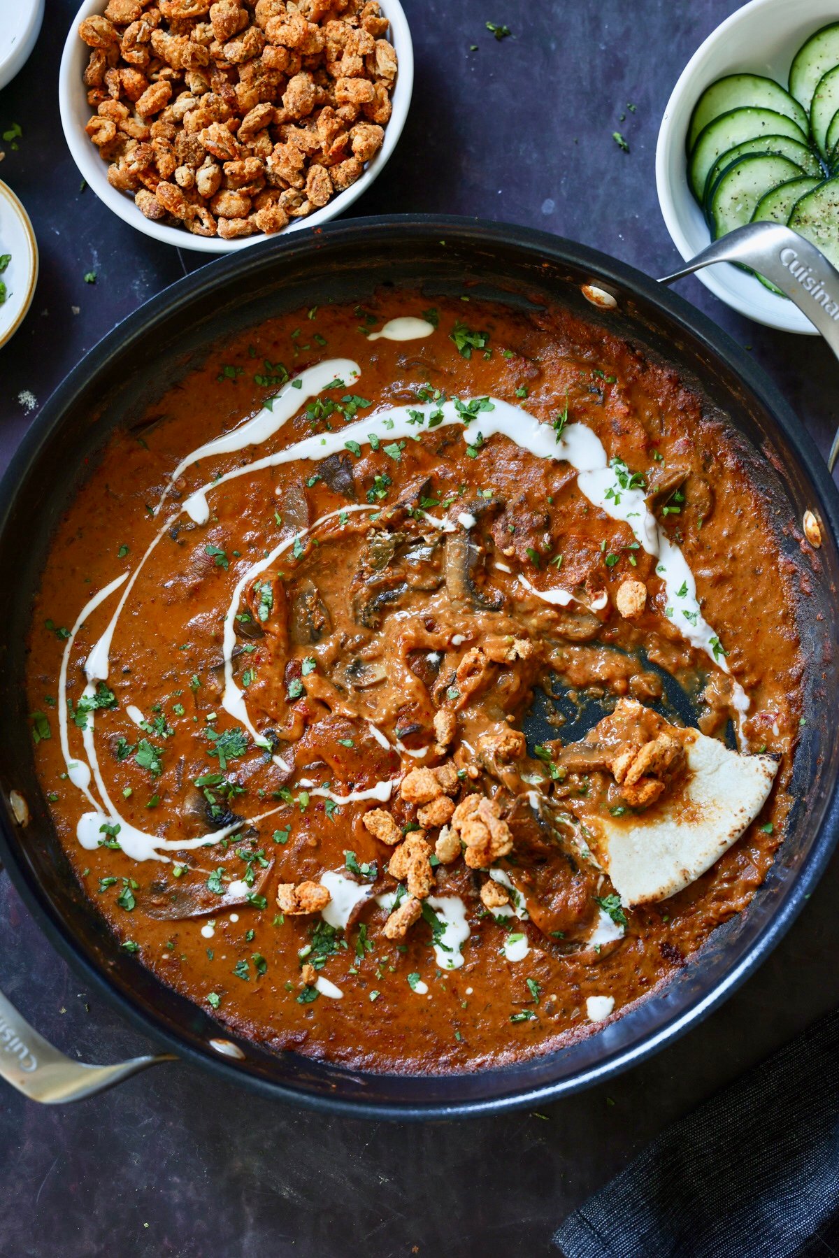 pan of cooked balchao mushrooms with a piece of flatbread dipped into it