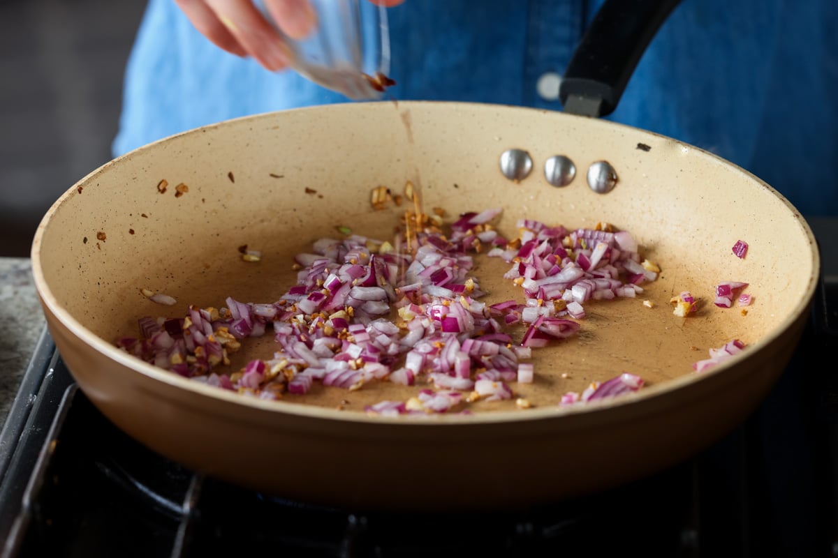 adding chili flakes to the pan