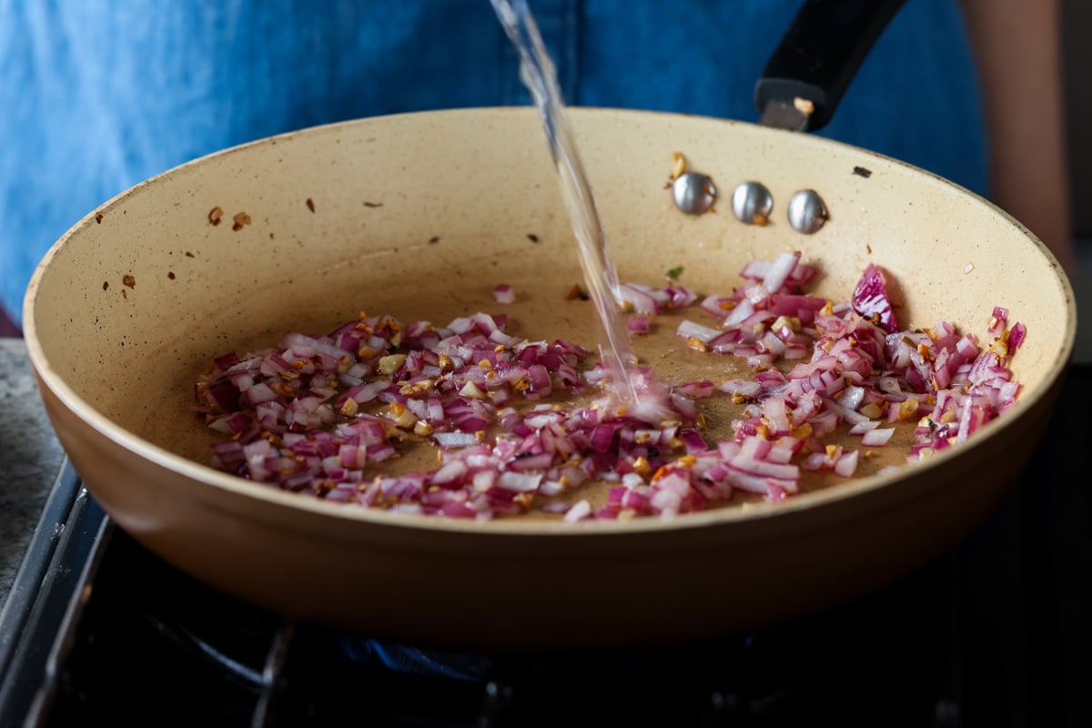 adding chili flakes and water to the pan