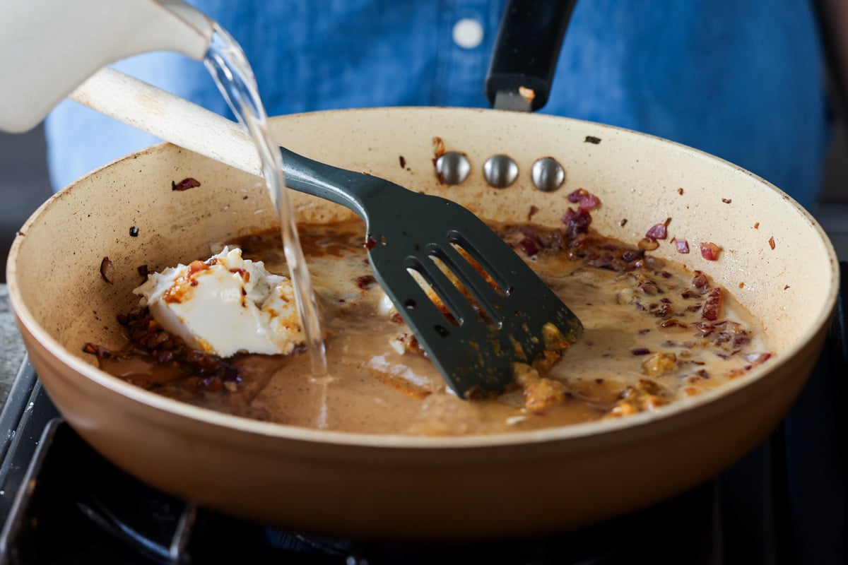 adding vegan cream cheese and water to the pan