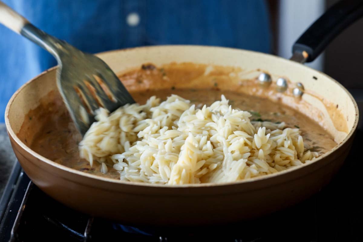 adding orzo to the pan