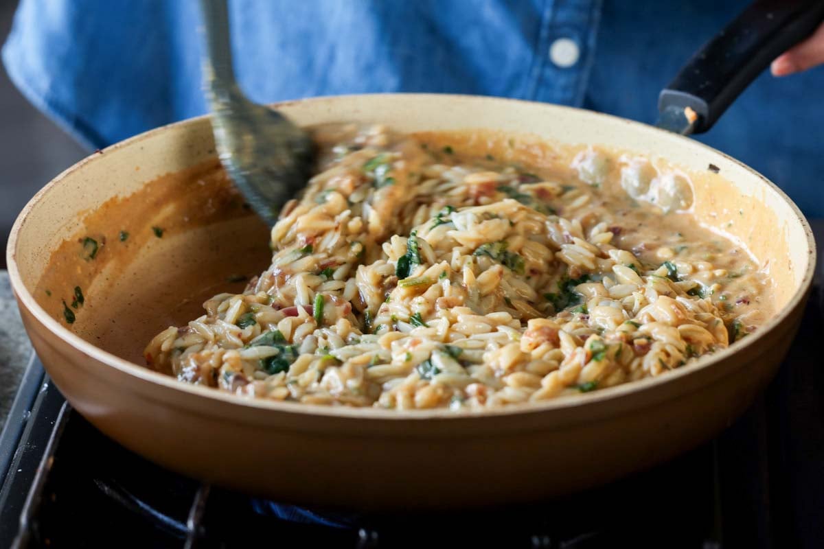 mixing together the orzo, spinach, and sauce