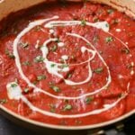 pan of vegan Kashmiri lal paneer topped with non-dairy yogurt