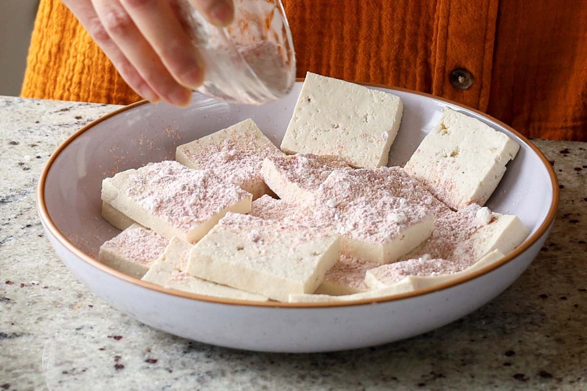 adding cornstarch and spices to the tofu