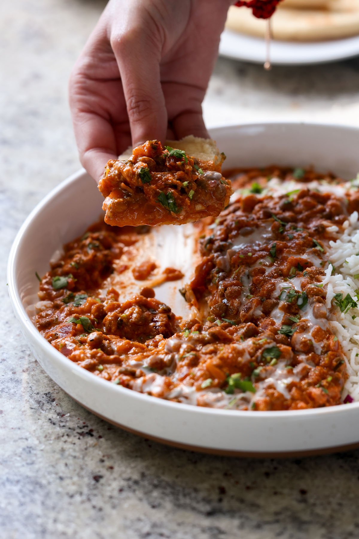 hand scooping up South Indian marry me lentils with flatbread