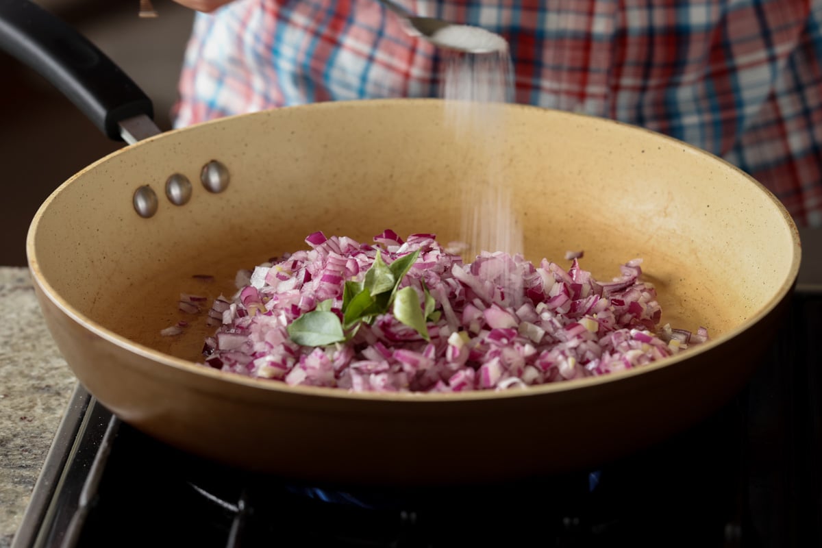 adding onions, curry leaves, and salt to the pan
