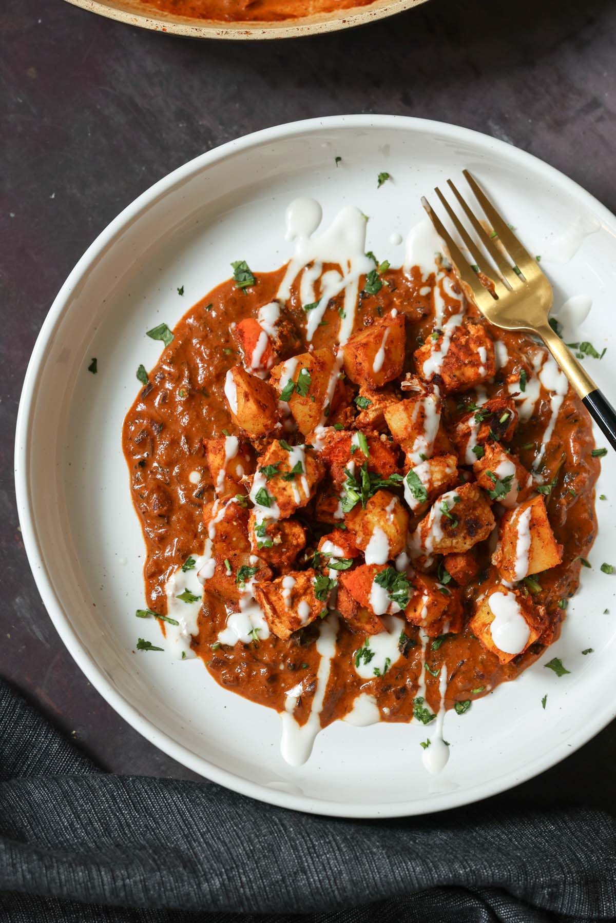 paneer ghee roast on a plate with yogurt and cilantro