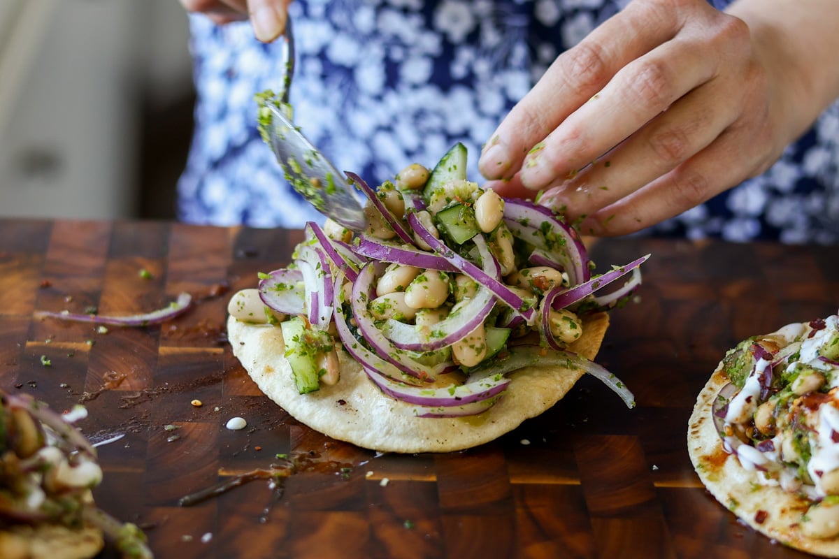 spooning the white bean mixture onto the tostadas
