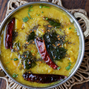 Mango dal in a silver dish topped with chilis.