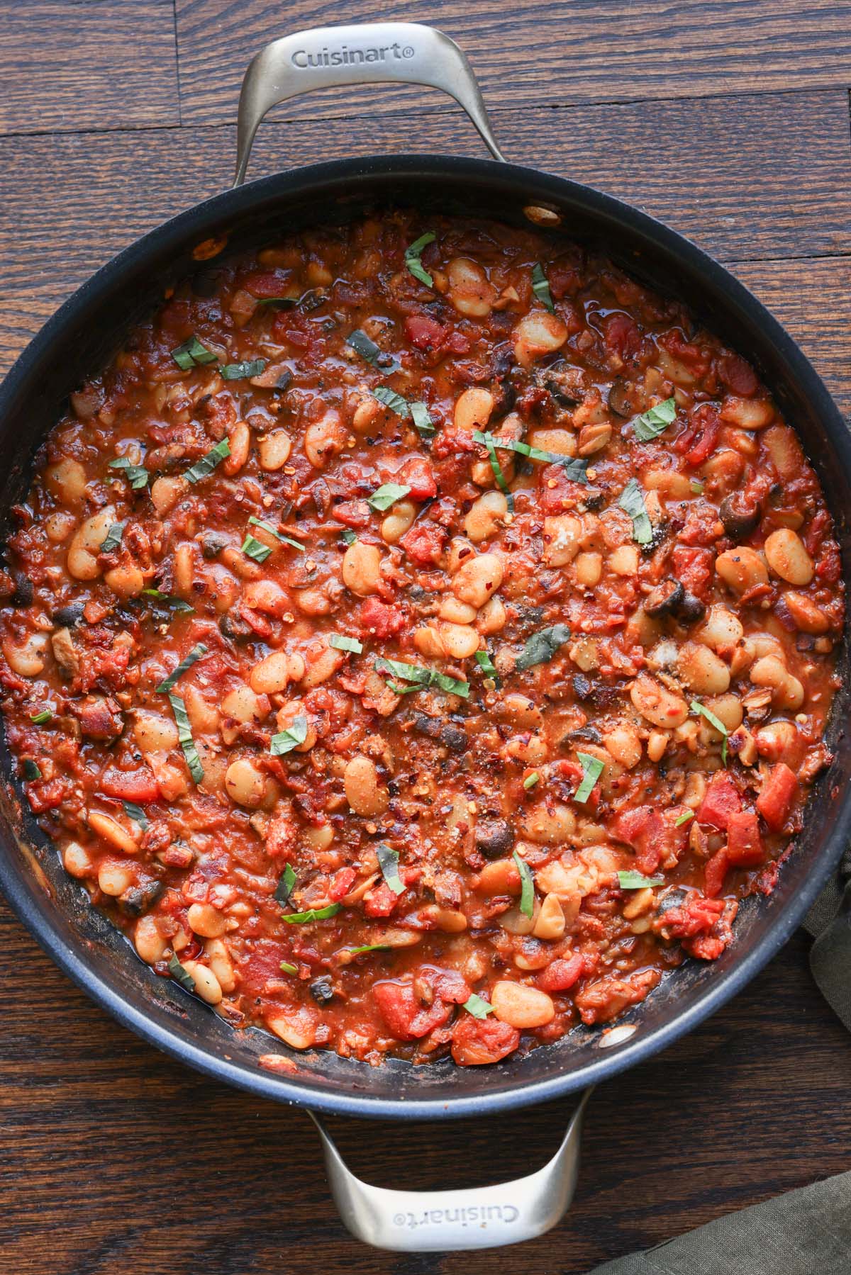 pan of puttanesca beans on a wooden table