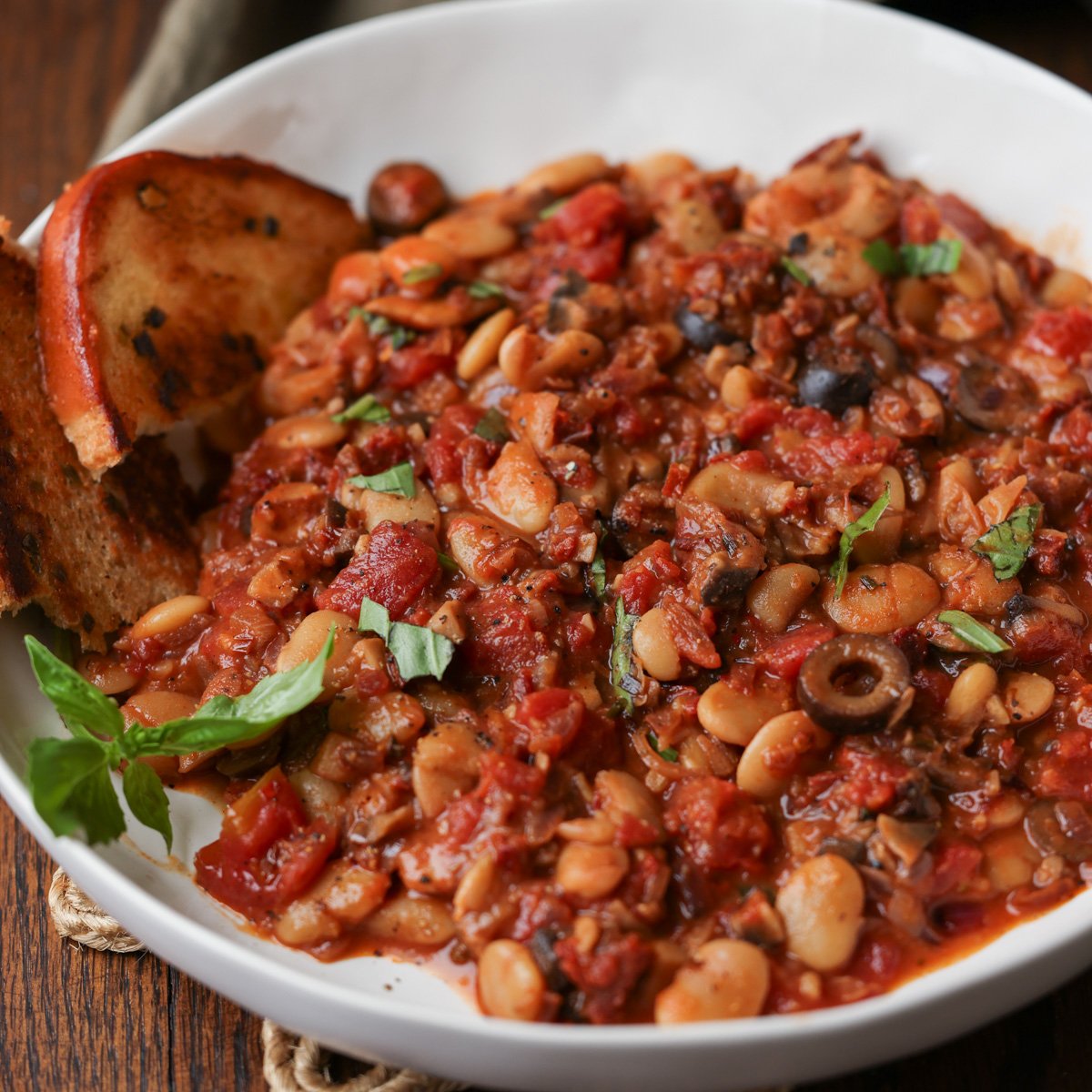 puttanesca beans on a plate with garlic bread