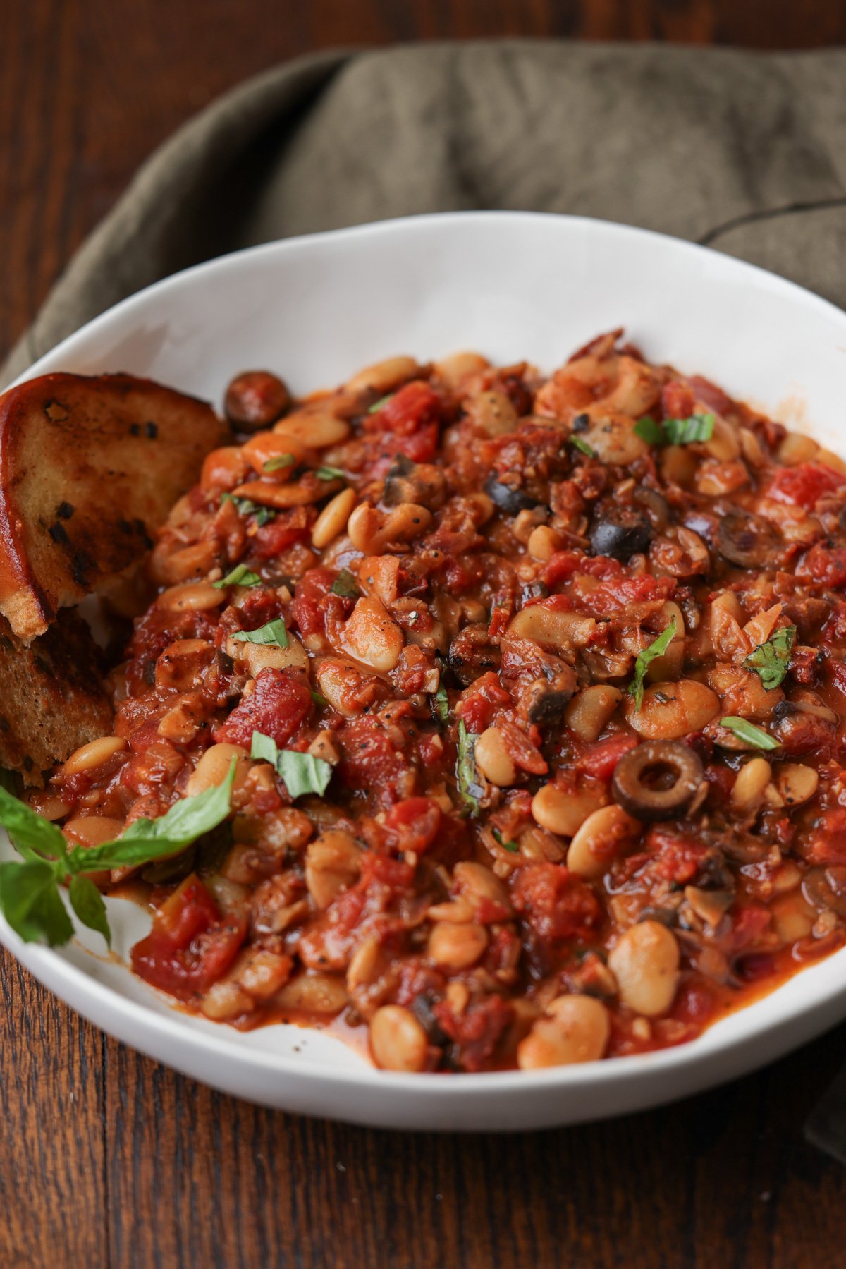 puttanesca beans on a plate with garlic bread