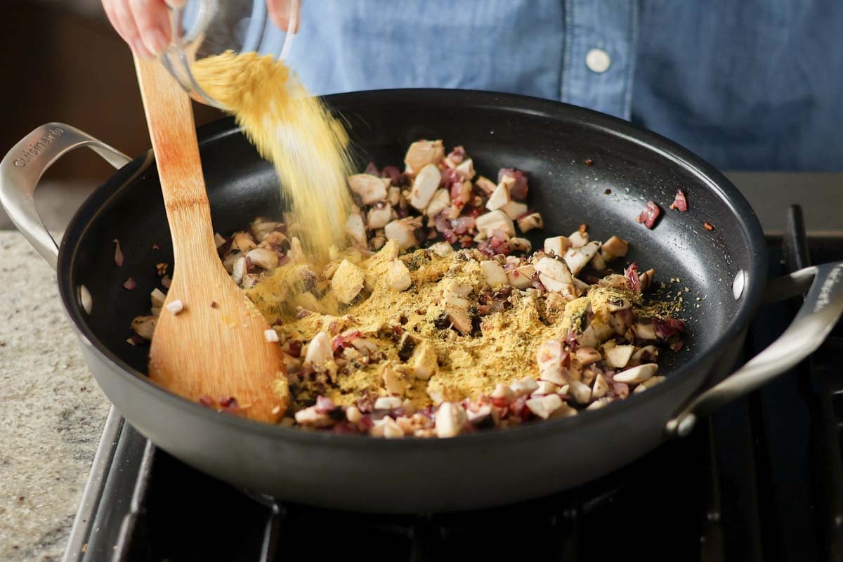 adding mushrooms and nutritional yeast to the pan
