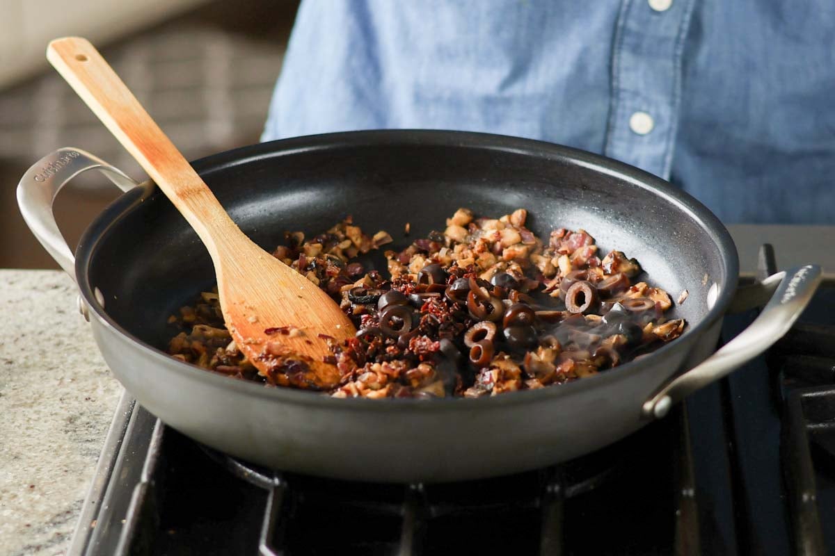 adding olives and sun dried tomatoes to the pan